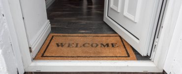 Tapis d'accueil welcome positionné sur le pas d'une porte ouverte