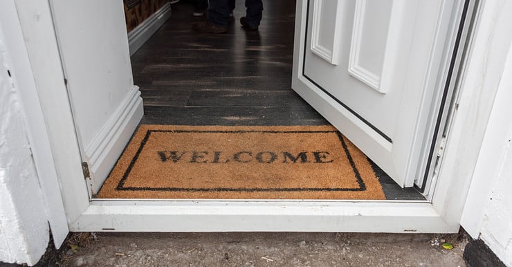 Tapis d'accueil welcome positionné sur le pas d'une porte ouverte