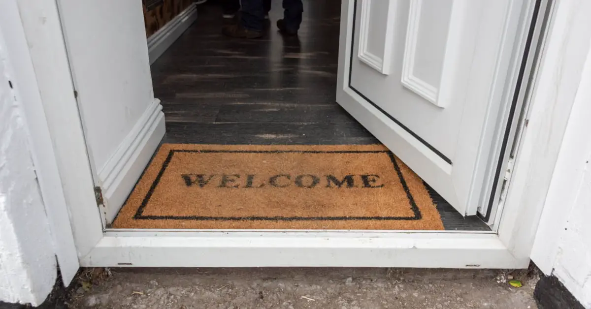 Tapis d'accueil welcome positionné sur le pas d'une porte ouverte