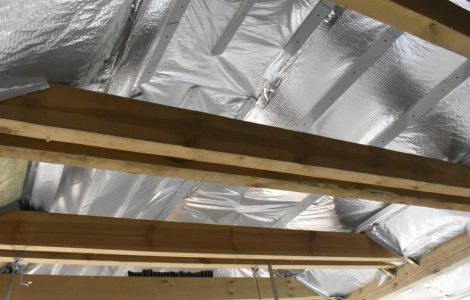 Isolation du toit par l'intérieur, vue sur les poutres en bois et le film d'isolation thermique