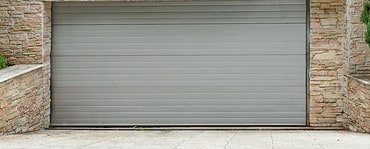 Vue sur une porte de garage à enroulement et des murs en pierre