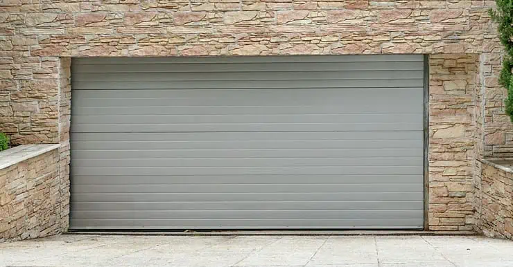 Vue sur une porte de garage à enroulement et des murs en pierre