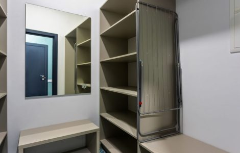 Un dressing avec des étagères vides et un miroir