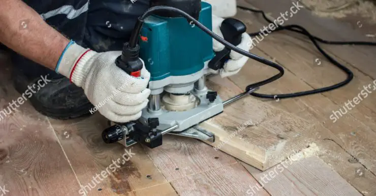 Zoom sur les mains d’un homme utilisant un rouleur électrique pour couper une planche en bois