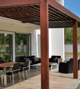 Vue sur une table et des chaises de jardin sous une pergola en bois