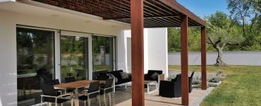 Vue sur une table et des chaises de jardin sous une pergola en bois