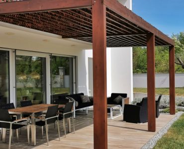 Vue sur une table et des chaises de jardin sous une pergola en bois