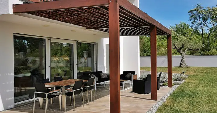 Vue sur une table et des chaises de jardin sous une pergola en bois