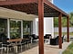 Vue sur une table et des chaises de jardin sous une pergola en bois