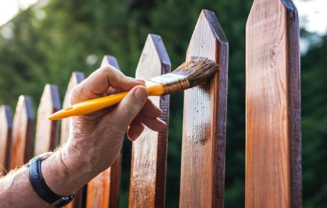 Zoom sur la main d'un homme appliquant un vernis sur une clôture en bois