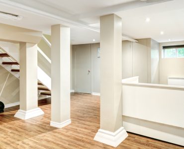 Un sous-sol avec plancher en bois et piliers blancs