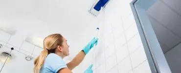 Une femme avec des gants bleus nettoie le plafond avec un mop