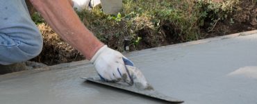 Un homme réalise les travaux de finition d'une allée en béton