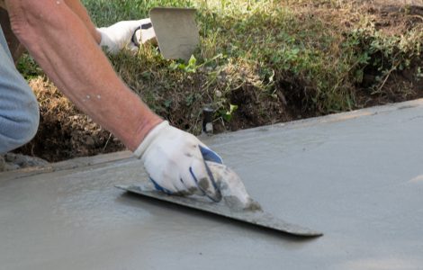 Un homme réalise les travaux de finition d'une allée en béton