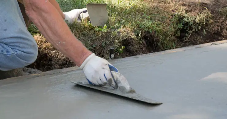 Un homme réalise les travaux de finition d'une allée en béton