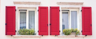Deux fenêtres italiennes avec volets classiques de couleur rouge vif
