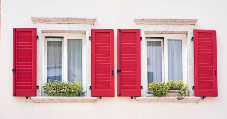 Deux fenêtres italiennes avec volets classiques de couleur rouge vif