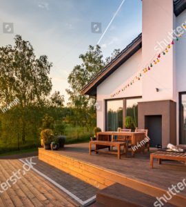 Une maison moderne avec une terrasse en bois et des meubles de jardin en bois