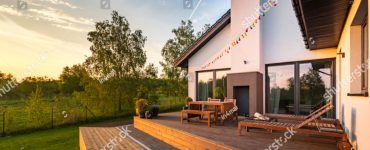 Une maison moderne avec une terrasse en bois et des meubles de jardin en bois