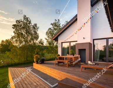 Une maison moderne avec une terrasse en bois et des meubles de jardin en bois