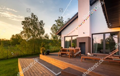 Une maison moderne avec une terrasse en bois et des meubles de jardin en bois