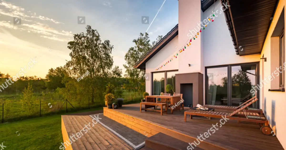Une maison moderne avec une terrasse en bois et des meubles de jardin en bois