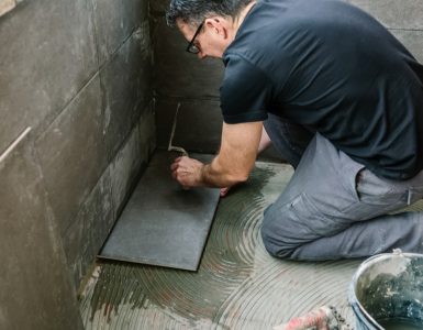 Un homme à lunette commence à carreler une terrasse