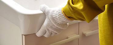 Un homme avec des gants blancs positionne le lavabo