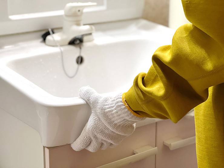 Un homme avec des gants blancs positionne le lavabo