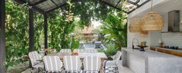 Cuisine extérieure avec table à manger sous une toiture de plantes grimpantes