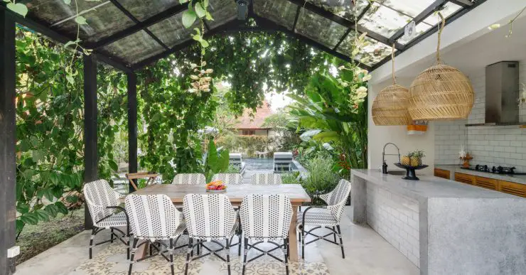 Cuisine extérieure avec table à manger sous une toiture de plantes grimpantes