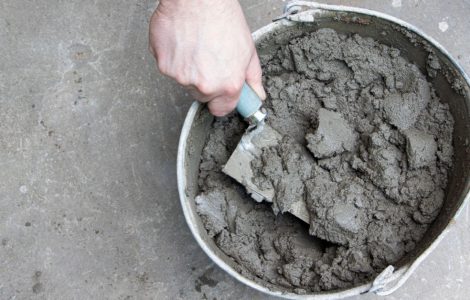 Zoom sur la main d'un homme mélangeant du mortier dans un seau