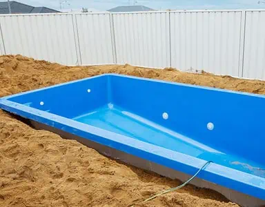 Installation d'une piscine en plastique bleu dans le sol