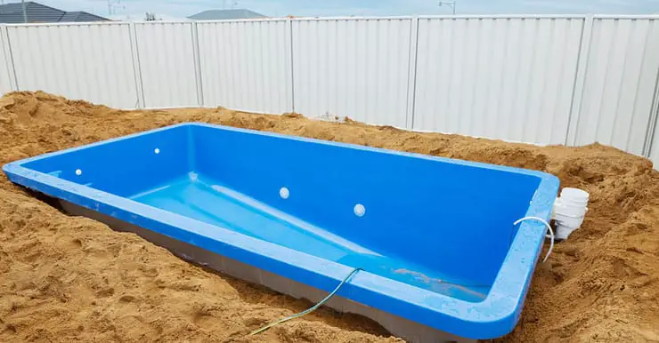 Installation d'une piscine en plastique bleu dans le sol