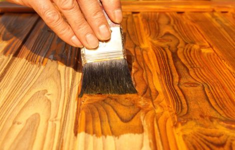 Zoom sur une main vernissant un meuble en bois avec un pinceau