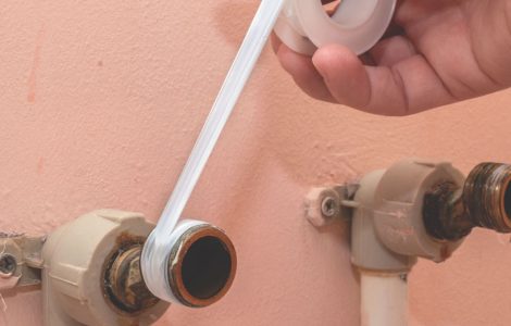 Zoom sur la main d’un homme assurant l’étanchéité d’une arrivée d’eau à l’aide de téflon