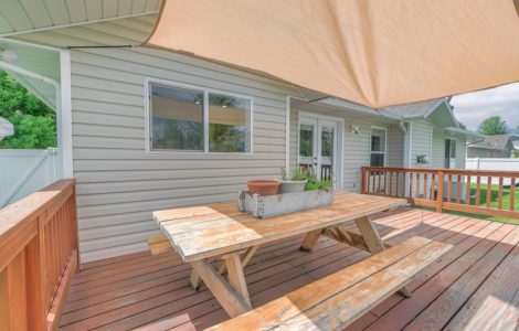 Table de jardin sur la terrasse en bois avec un voile d'ombrage