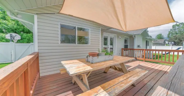 Table de jardin sur la terrasse en bois avec un voile d'ombrage