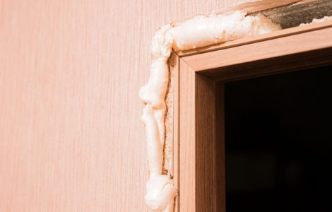 Zoom sur une couche de mousse polyuréthane insérée dans les trous autour de la porte