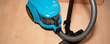 Un aspirateur de couleur bleue posé sur le sol en parquet