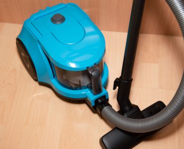 Un aspirateur de couleur bleue posé sur le sol en parquet