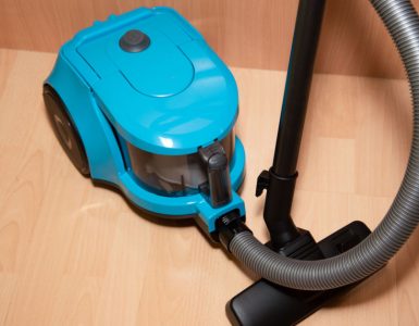 Un aspirateur de couleur bleue posé sur le sol en parquet