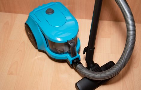 Un aspirateur de couleur bleue posé sur le sol en parquet
