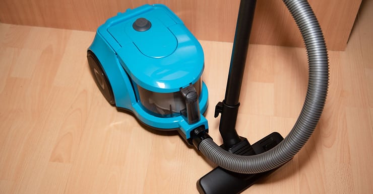 Un aspirateur de couleur bleue posé sur le sol en parquet