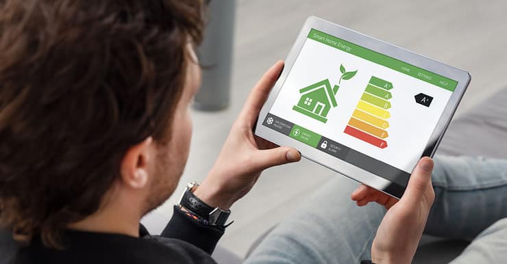 Un homme regarde une tablette affichant l'efficacité énergétique d'une maison à l'écran