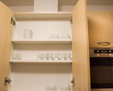 Placard de cuisine en bois avec des tasses blanches à l'intérieur