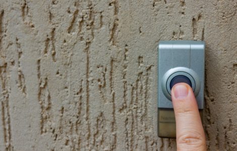 Zoom sur le doigt d'une personne appuyant sur la sonnette de porte
