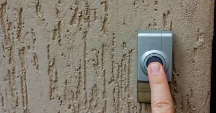 Zoom sur le doigt d'une personne appuyant sur la sonnette de porte