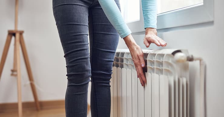 Une femme se chauffant les mains sur le radiateur