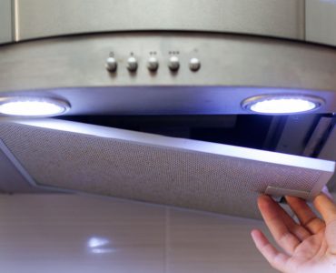 Zoom sur la main d’une personne ouvrant la hotte aspirante